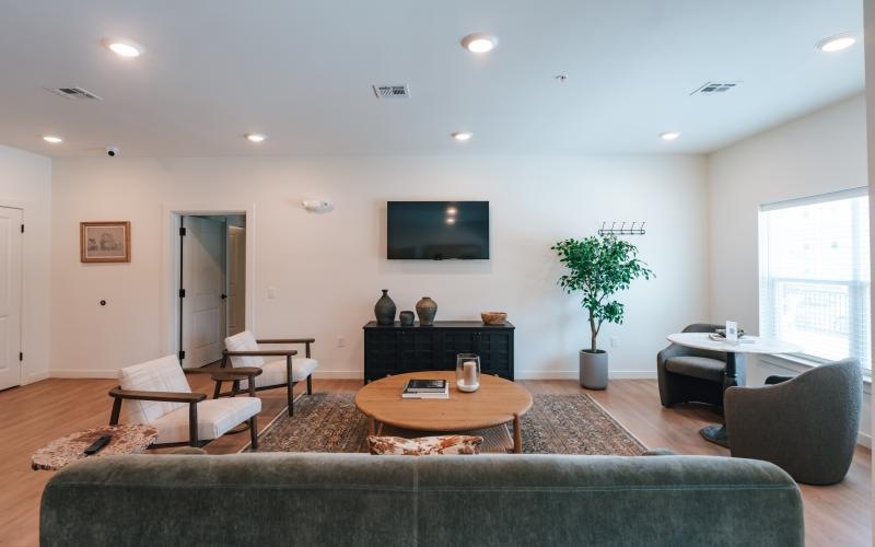 a clubroom with a tv, couch, tables and chairs